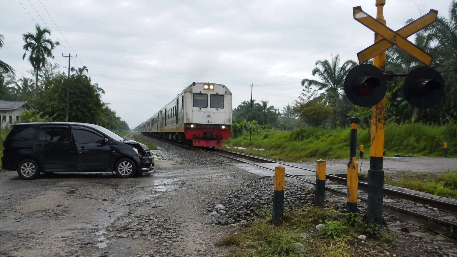 Perlintasan rel kereta tanpa palang di kawasan permukiman dengan rambu peringatan terlihat jelas